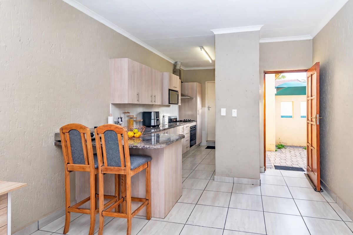 Functional kitchen featuring light wood cabinetry, granite countertops, built-in oven, hob, and a breakfast nook, with direct access to an outdoor area.