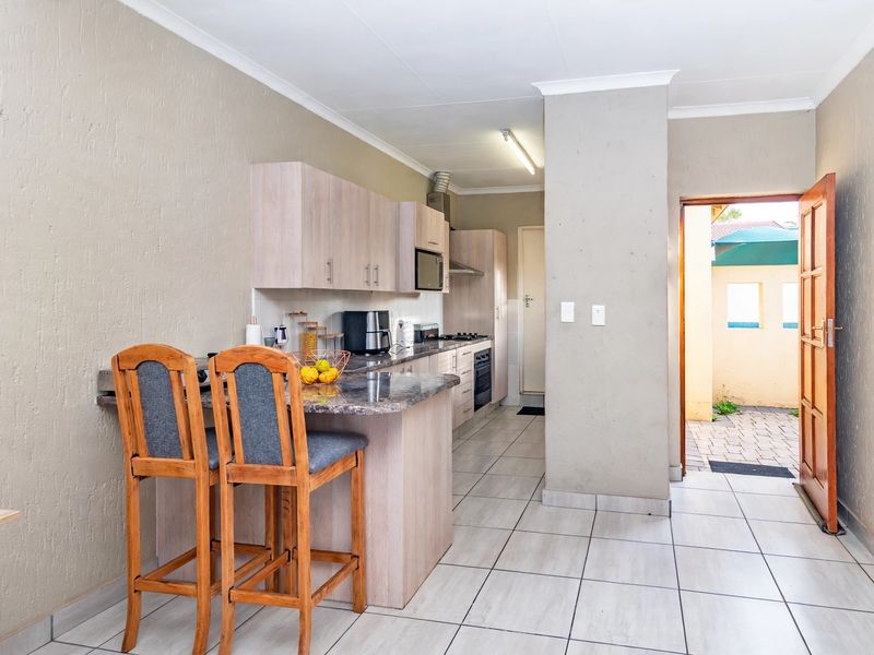 Functional kitchen featuring light wood cabinetry, granite countertops, built-in oven, hob, and a breakfast nook, with direct access to an outdoor area.