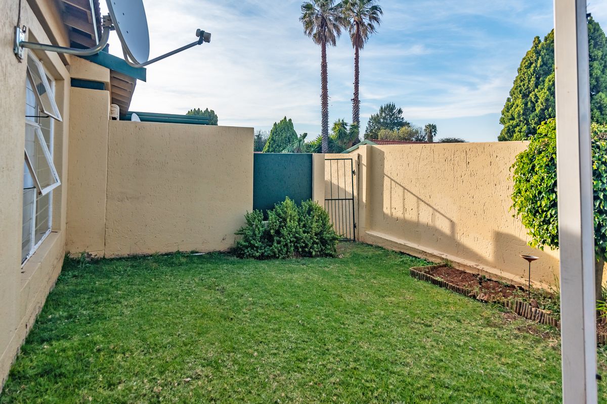 A private rear garden area featuring a lawn, boundary walls, and a metal access gate.