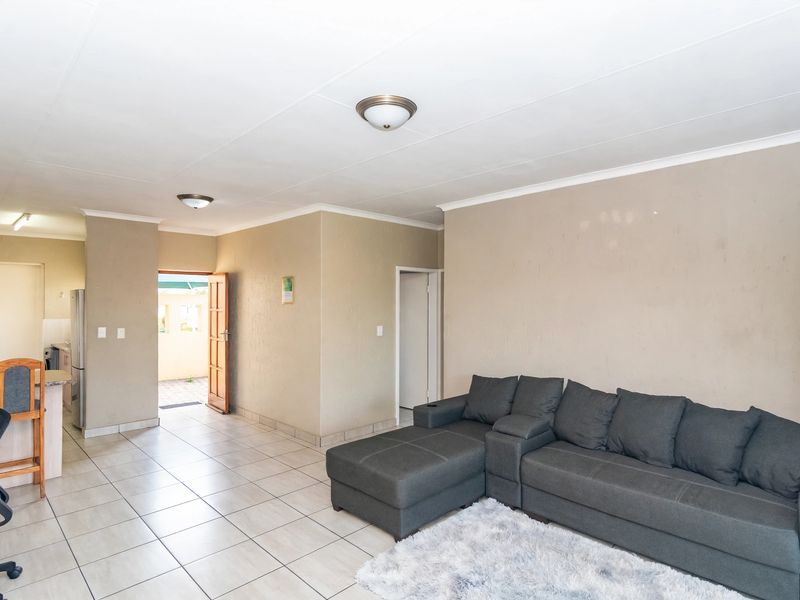 Open-plan living area featuring neutral wall tones, tiled flooring, and direct access to an exterior entrance, providing a functional and versatile living space.