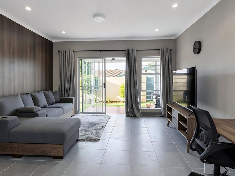 Modern living room featuring tiled floors, a wood-look feature wall, and sliding glass doors providing direct access to the rear patio and garden.