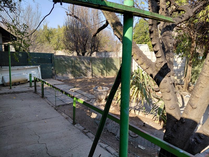Rear garden area featuring a concrete patio, wire fencing, and boundary wall, requiring landscaping and maintenance to improve outdoor appeal.