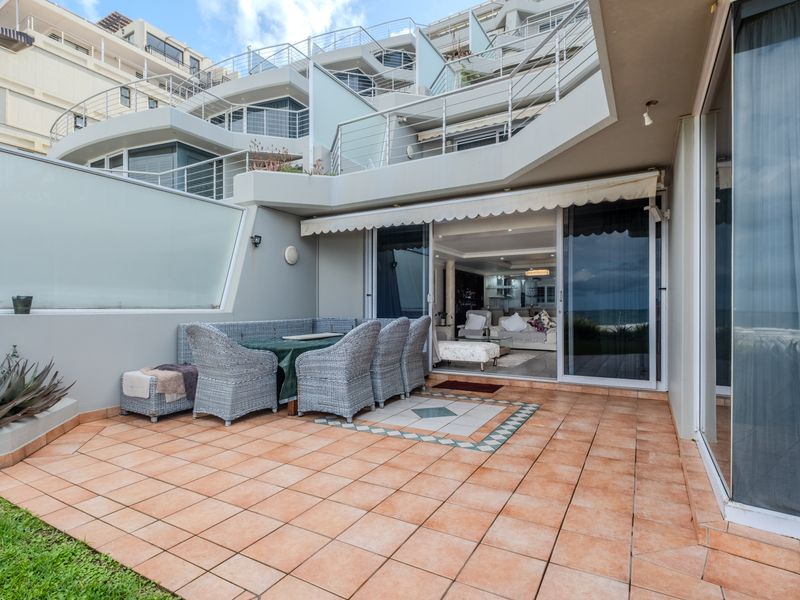 Spacious ground-floor patio featuring tiled flooring, a retractable awning, and direct access to the interior living area through large sliding glass doors.