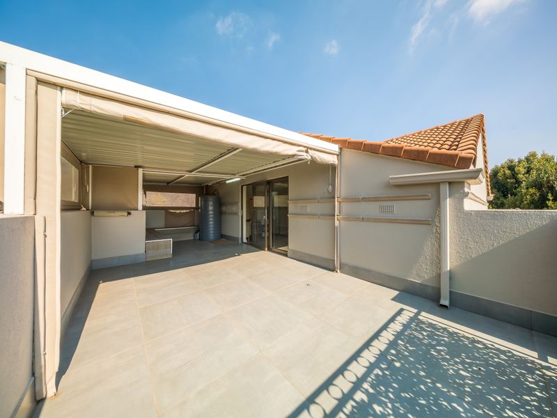 A spacious covered patio featuring tiled flooring and direct access to the interior through sliding glass doors, ideal for outdoor entertaining.