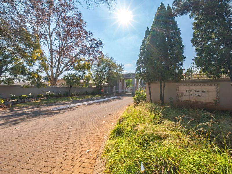Entrance view of Van Buuren Estate featuring a paved driveway, secure gated access, and established perimeter walling.