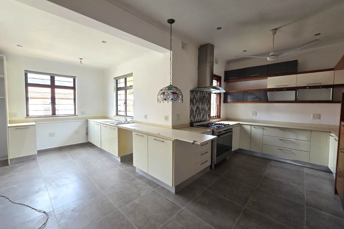 Spacious kitchen featuring neutral cabinetry, tiled flooring, a gas stove with extractor fan, and ample counter space.