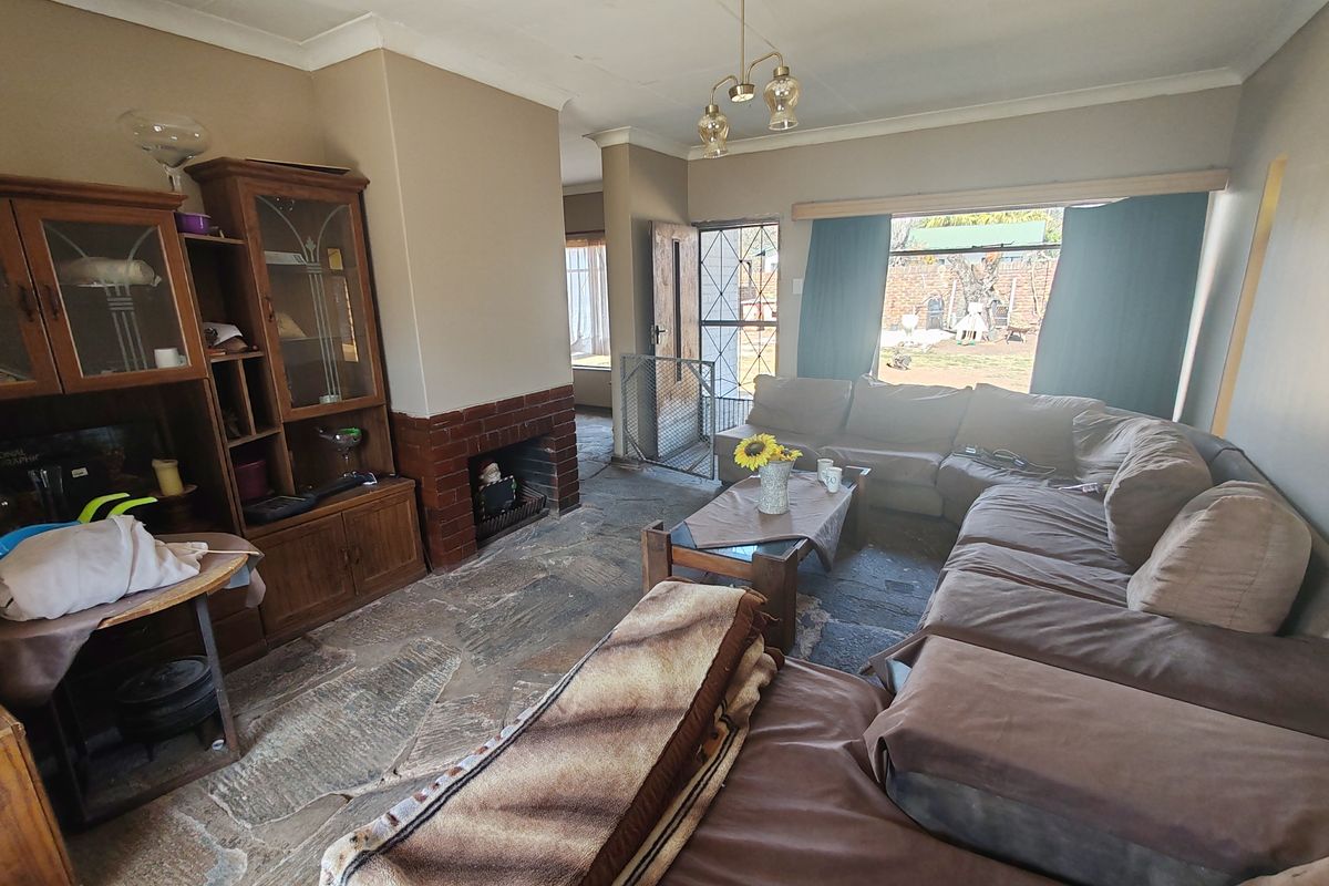 A living room featuring a brick fireplace and natural stone flooring, offering direct access to the rear garden through a security gate.