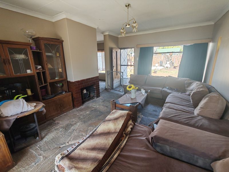 A living room featuring a brick fireplace and natural stone flooring, offering direct access to the rear garden through a security gate.