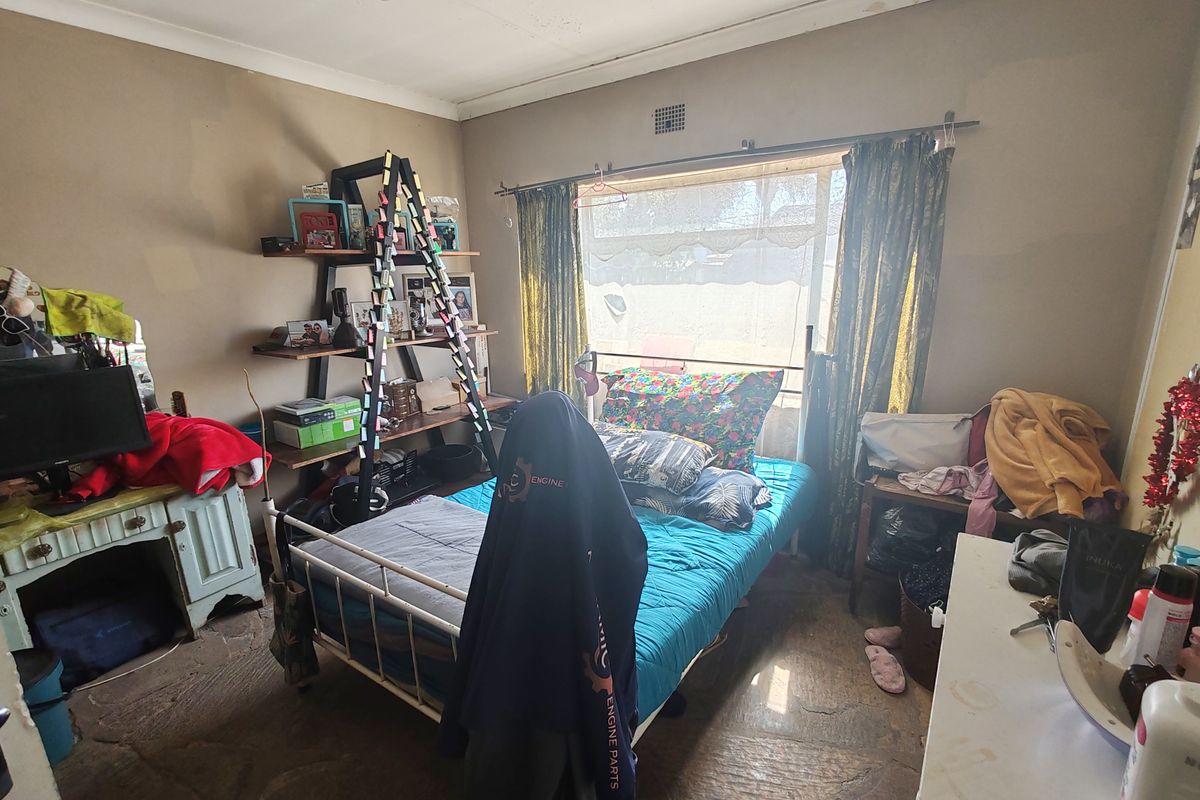 A bedroom featuring stone flooring, coving, and a ventilation grille, currently requiring cosmetic updates to the wall finishes.