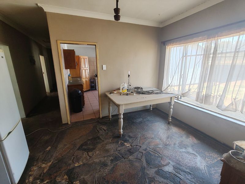 Dining area featuring natural stone flooring, large window with natural light, and direct access to the kitchen area.