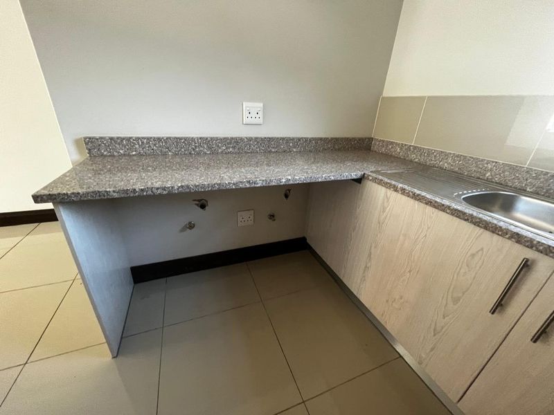 A functional laundry area featuring a laminate countertop, built-in cabinetry, and a stainless steel sink with dedicated plumbing connections.