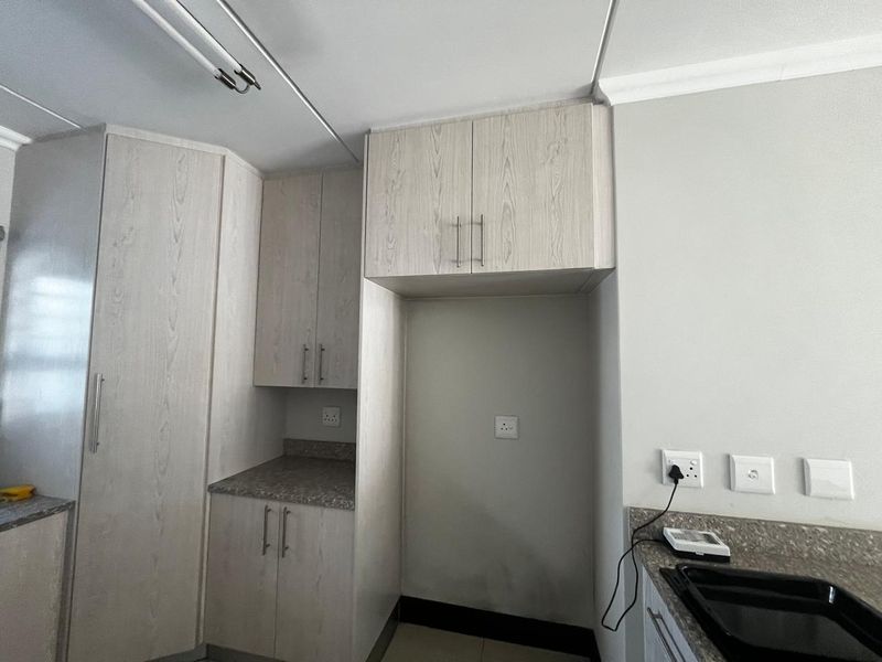 A clean, empty kitchen area featuring light wood-grain built-in cabinetry, stone-look countertops, and dedicated space for appliances with integrated electrical points.