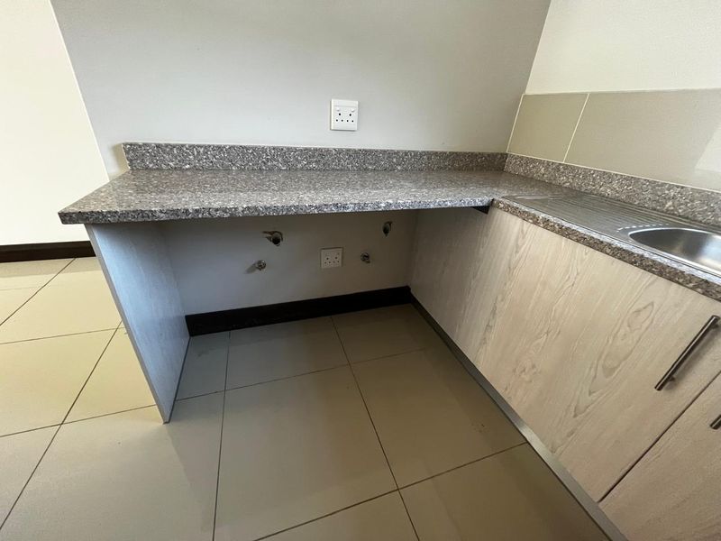 A clean and functional laundry area featuring a durable countertop, integrated sink, and dedicated plumbing connections for a washing machine.