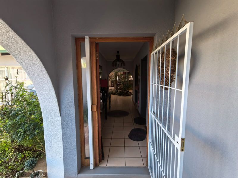 Entrance area featuring a security gate, tiled flooring, and an arched architectural detail leading into the home interior.