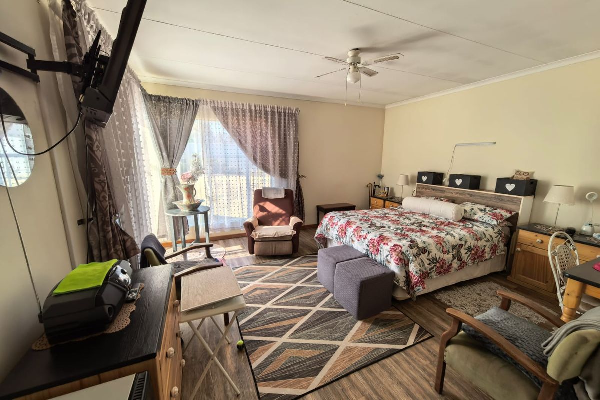 Spacious bedroom featuring laminate flooring, a ceiling fan, and a sliding glass door providing natural light.