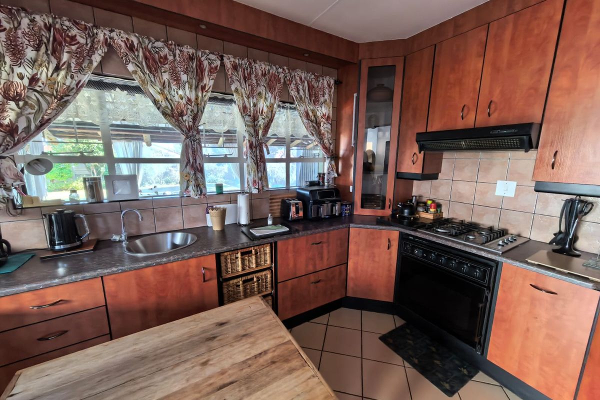 A functional kitchen featuring wood-look laminate cabinetry, tiled backsplash, gas hob, built-in oven, and ceramic tile flooring with ample counter space.