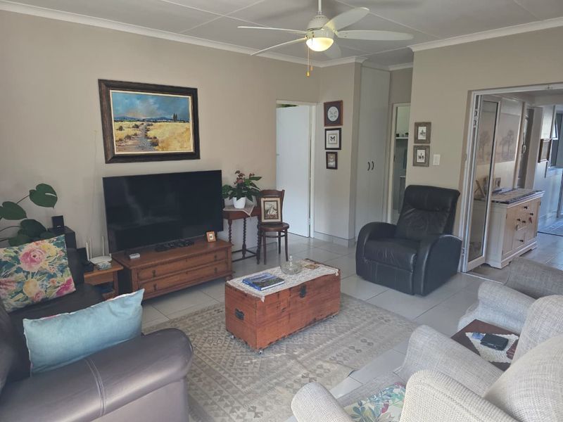 A comfortable living room featuring tiled flooring, a ceiling fan, and neutral wall tones, providing a functional and inviting space.