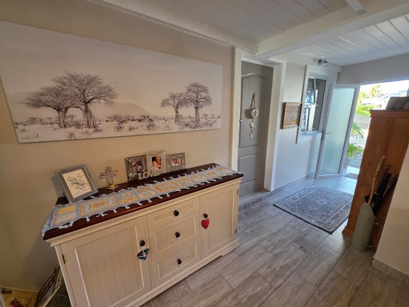 A bright and welcoming entrance hall featuring modern timber-look floor tiles and a painted timber ceiling, leading directly to the exterior.