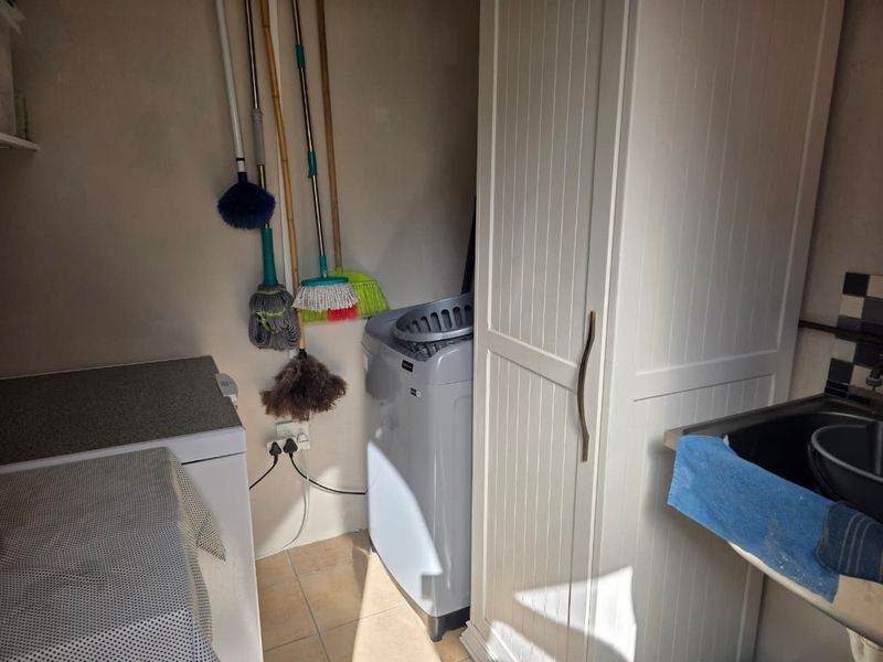 A functional laundry area featuring built-in cabinetry, a sink, and tiled finishes, providing practical utility space for household tasks.