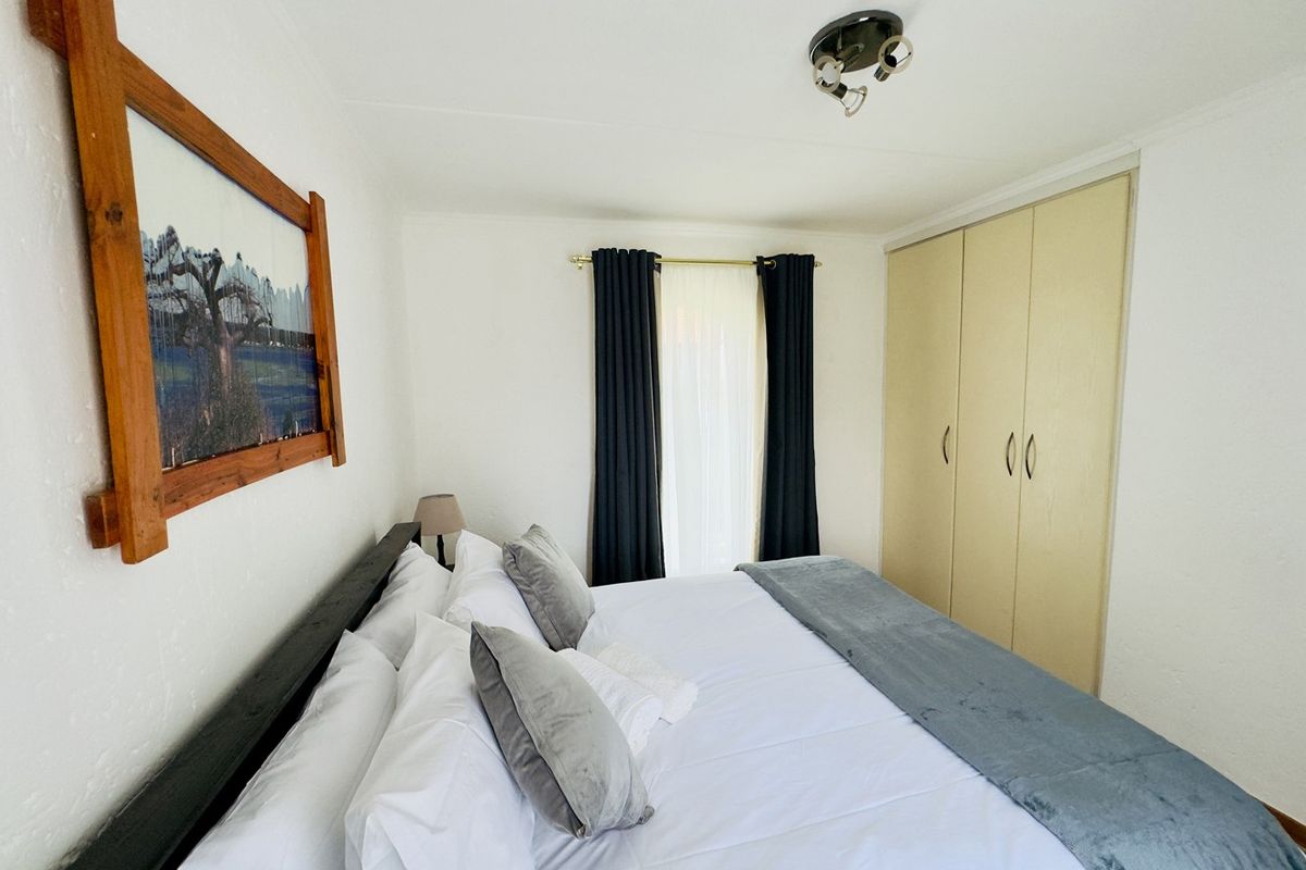 A bedroom featuring built-in cupboards, neutral walls, and a ceiling light fixture, providing a functional and tidy sleeping space.