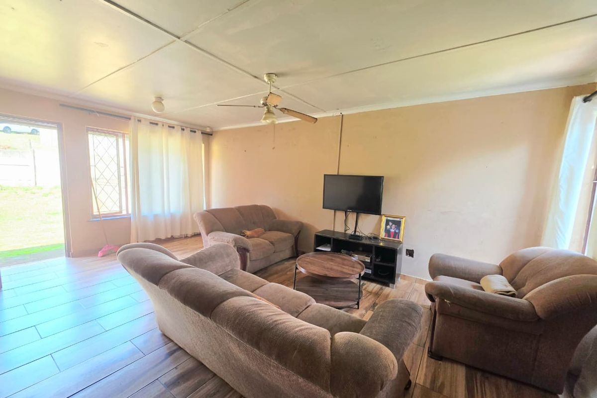 A living room featuring tiled flooring, a ceiling fan, and access to the exterior via a security gate.
