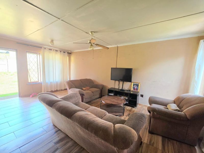 A living room featuring tiled flooring, a ceiling fan, and access to the exterior via a security gate.