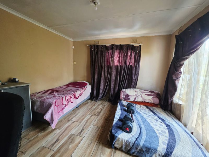 A bedroom featuring laminate flooring and neutral wall tones, providing a functional space that would benefit from cosmetic updates and fresh paint.