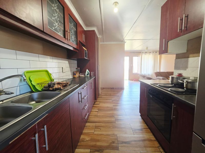 A functional kitchen featuring dark wood-look cabinetry, subway tile backsplash, double stainless steel sink, and built-in oven with electric hob.