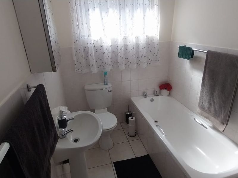 A functional bathroom featuring a pedestal basin, toilet, and a standard bathtub with tiled wall finishes.