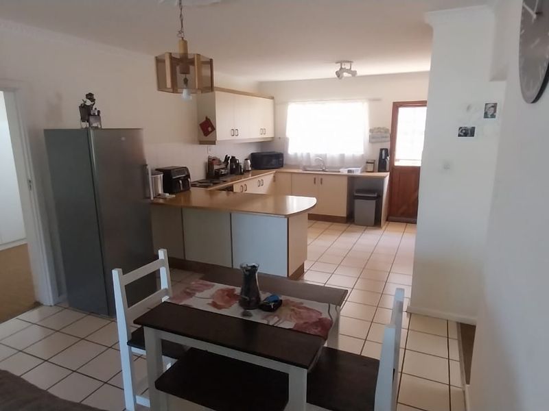 Open plan kitchen and dining area featuring tiled flooring, functional cabinetry, and a breakfast counter, providing a practical layout for daily living.