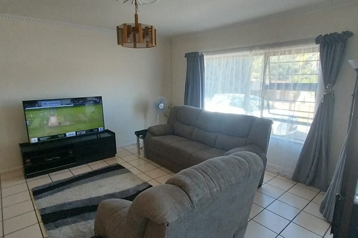 A living room featuring ceramic tile flooring, a ceiling rose, and a sliding glass door providing access to the exterior.