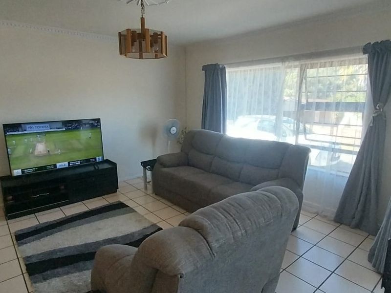 A living room featuring ceramic tile flooring, a ceiling rose, and a sliding glass door providing access to the exterior.