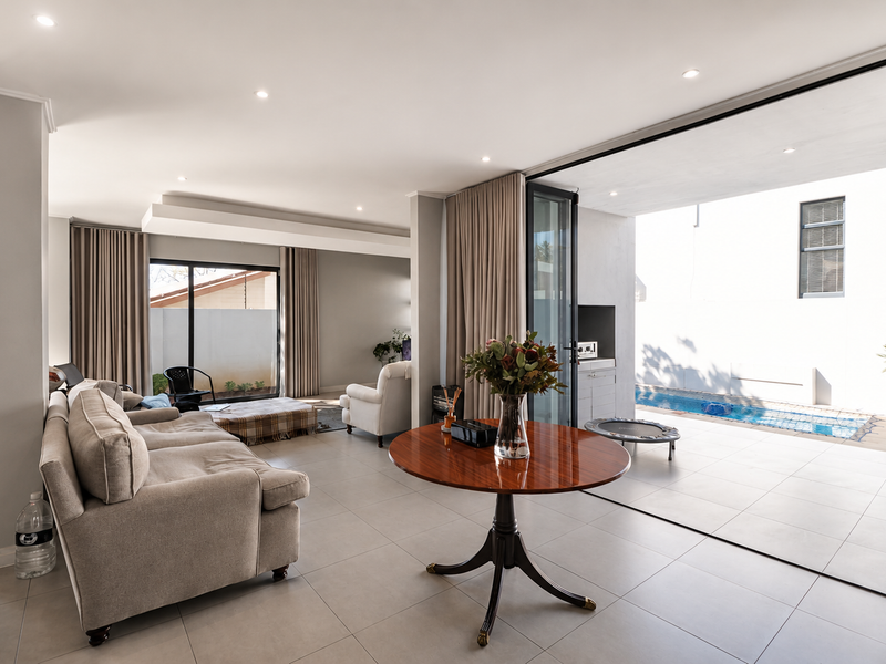 Spacious open-plan living area featuring large stacking glass doors that provide seamless indoor-outdoor flow to the patio and swimming pool area.