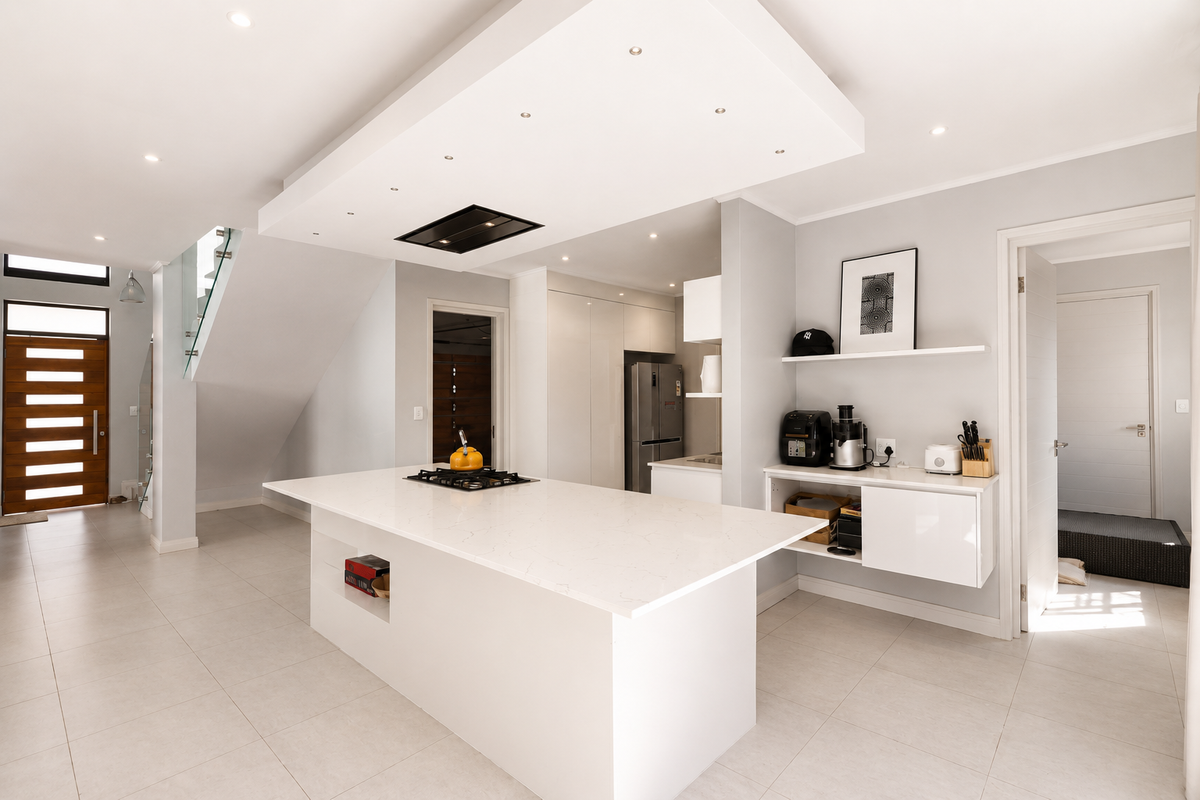 Modern open-plan kitchen featuring a large central island with quartz countertops, gas cooktop, sleek cabinetry, and recessed lighting in a contemporary drop ceiling.