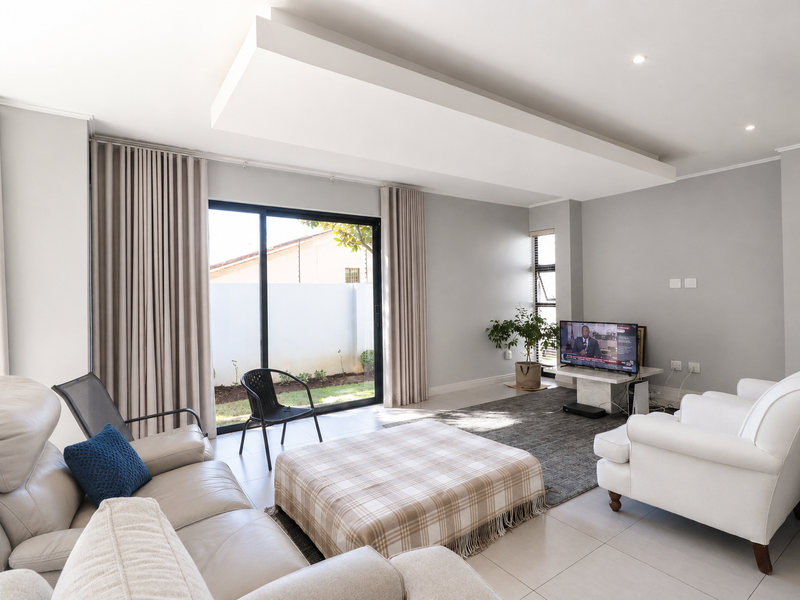 Spacious living room featuring a recessed ceiling detail, tiled flooring, and large sliding glass doors providing direct access to the outdoor area.