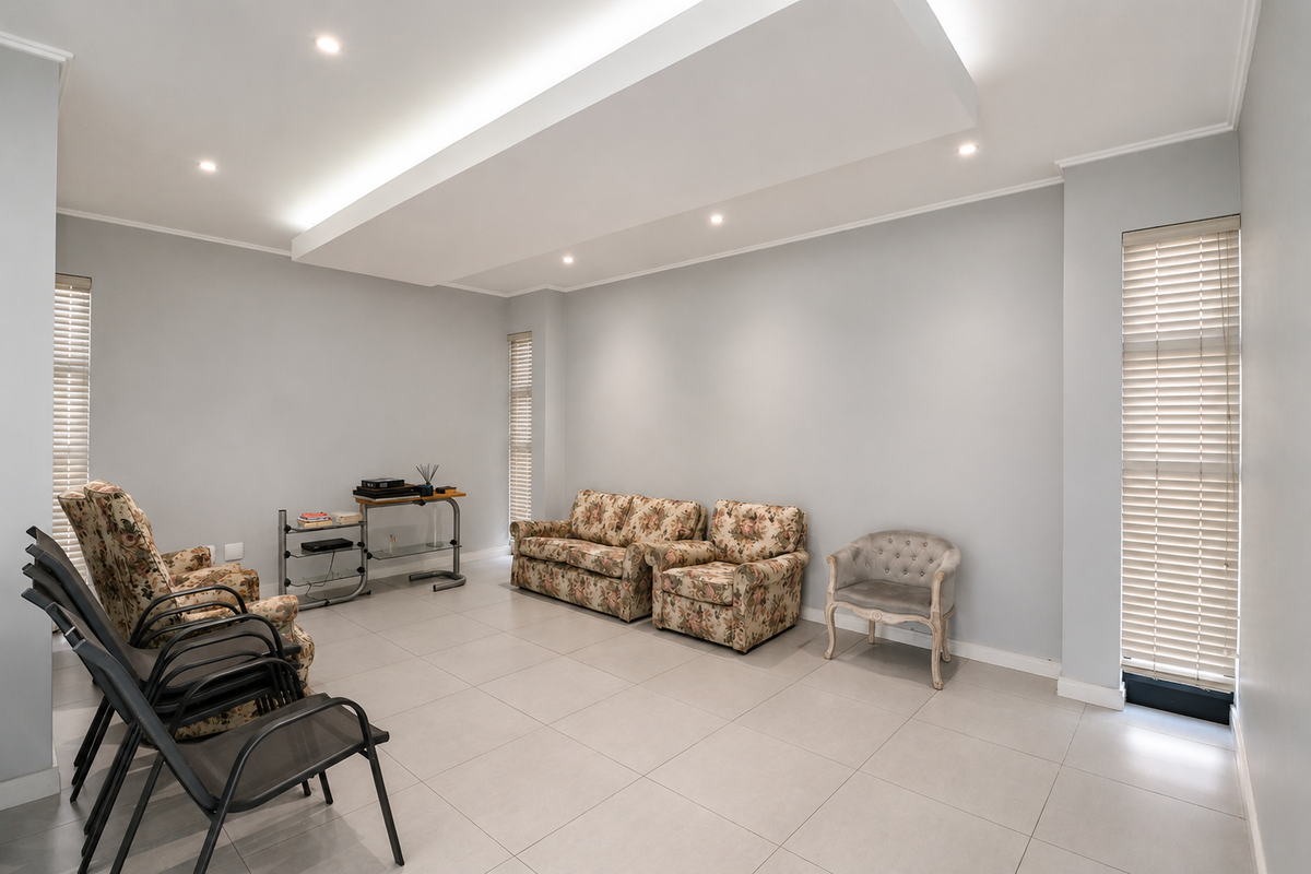 Spacious living room featuring neutral tiled flooring, a modern recessed ceiling with integrated downlighting, and large windows fitted with venetian blinds.