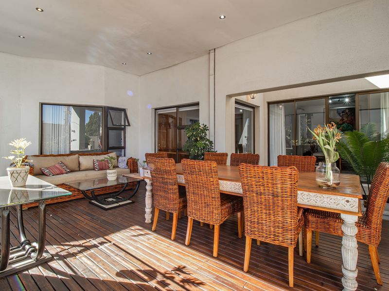 Spacious covered patio featuring timber decking, recessed lighting, and multiple access points to the interior living areas through large sliding glass doors.