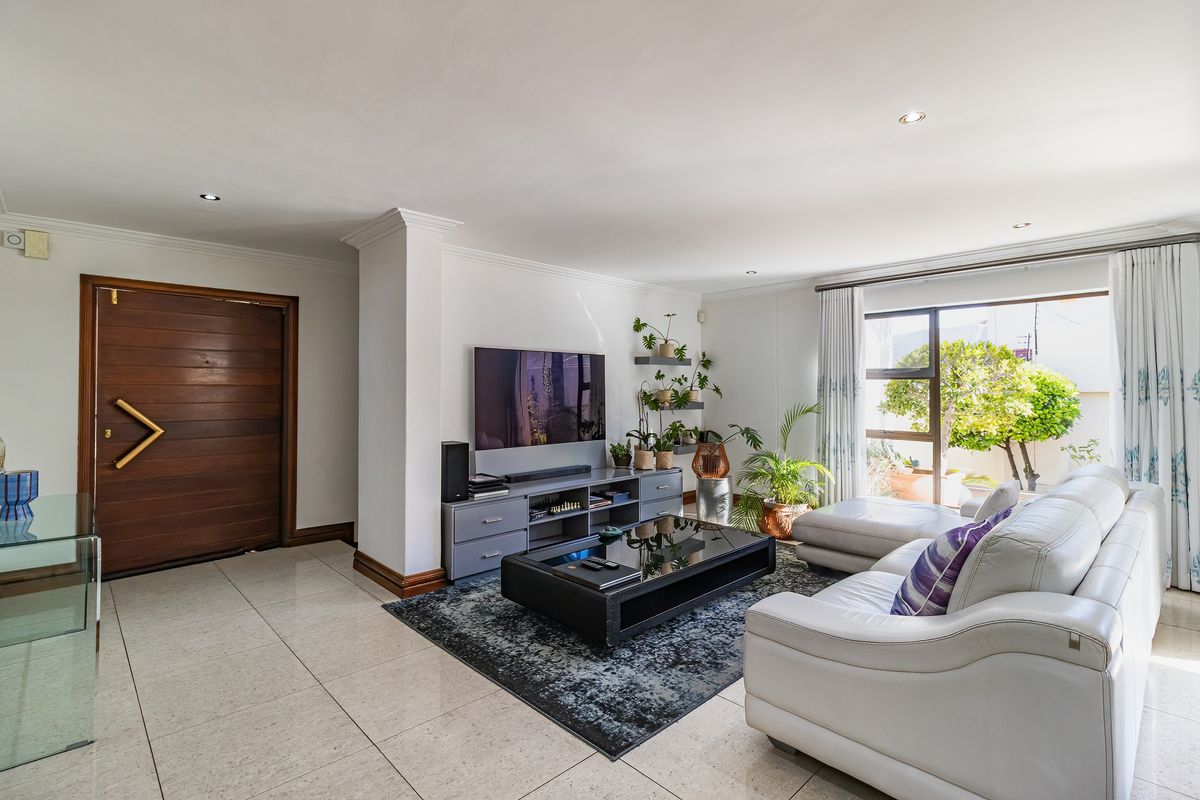 Spacious living room featuring large format floor tiles, recessed lighting, and a sliding glass door providing natural light and access to the garden.