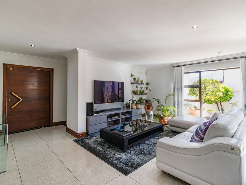 Spacious living room featuring large format floor tiles, recessed lighting, and a sliding glass door providing natural light and access to the garden.