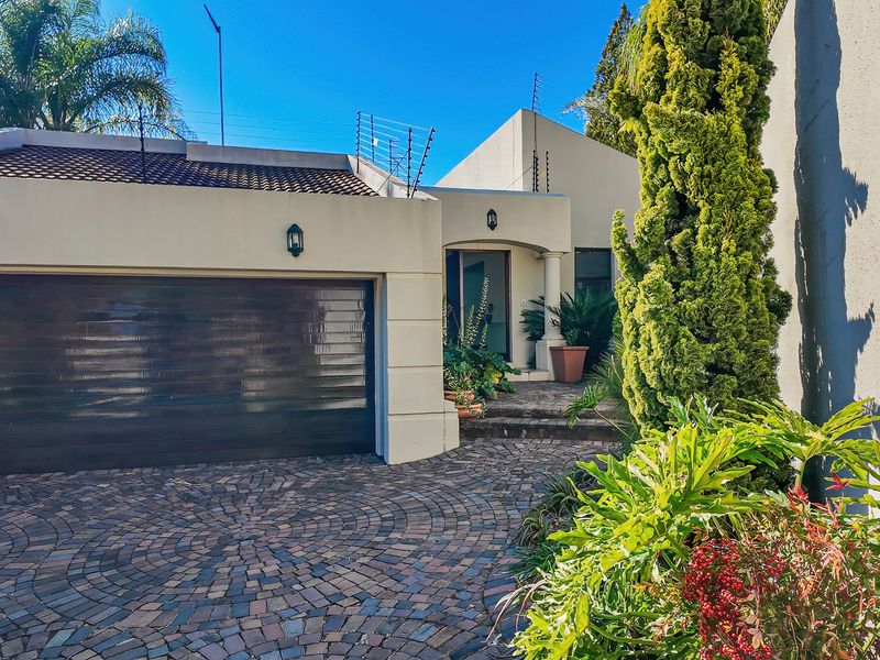 Front elevation of a cluster home featuring a paved driveway, double garage, and well-maintained entrance area with established landscaping.
