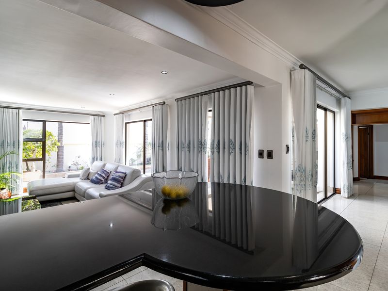 Spacious open-plan living area featuring polished black granite countertops, tiled flooring, and large sliding glass doors providing ample natural light.