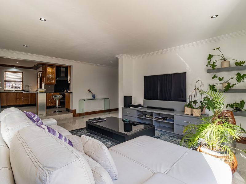 Spacious open-plan living area featuring tiled floors, recessed lighting, and a seamless transition to a well-appointed kitchen with built-in cabinetry.
