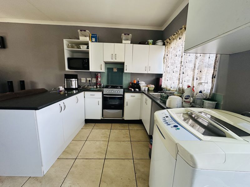 A functional kitchen featuring white cabinetry, dark laminate countertops, a freestanding oven, and tiled flooring with a practical layout.