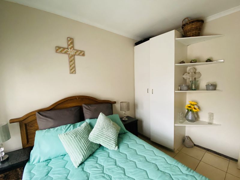 A bedroom featuring built-in wardrobe cabinetry and integrated corner shelving with tiled flooring.