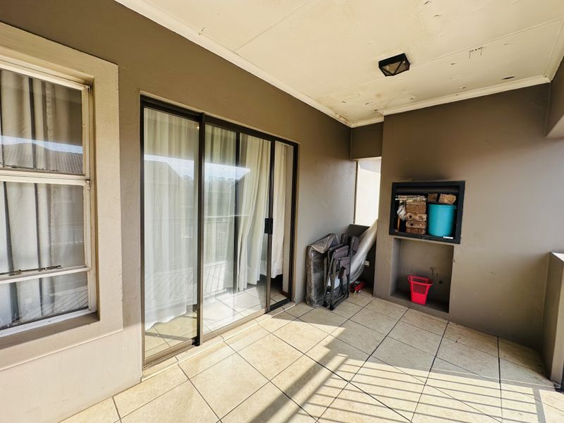 Covered balcony featuring tiled flooring, sliding glass doors, and a built-in braai area, requiring minor ceiling maintenance.