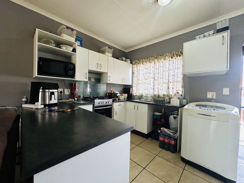 Functional kitchen featuring white cabinetry, dark laminate countertops, gas hob, oven, and tiled flooring with space for laundry appliances.