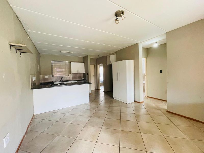 Open-plan living area featuring a functional kitchen with built-in cabinetry, dark countertops, and tiled flooring throughout the space.