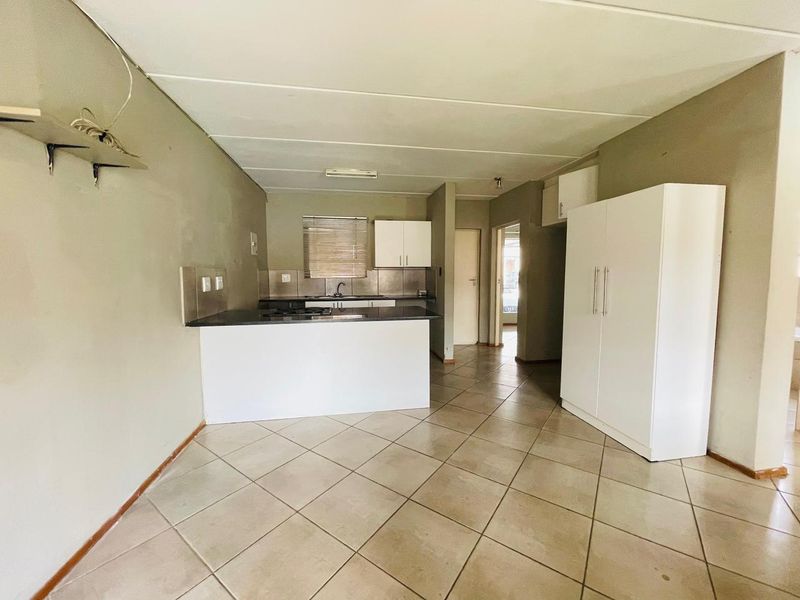 Open plan living and kitchen area featuring tiled flooring, built-in cabinetry, and a kitchen island with a hob.
