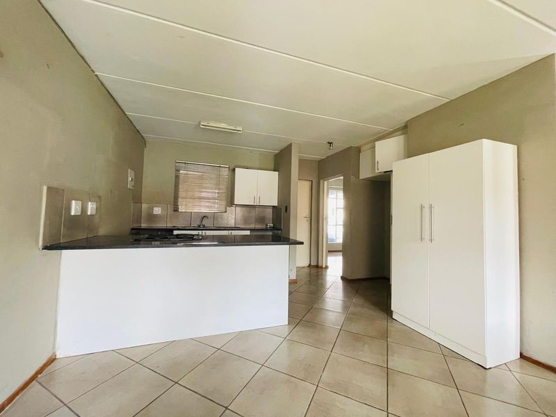 Open-plan kitchen and living area featuring tiled flooring, built-in cabinetry with stone countertops, and a functional layout suitable for modern living.