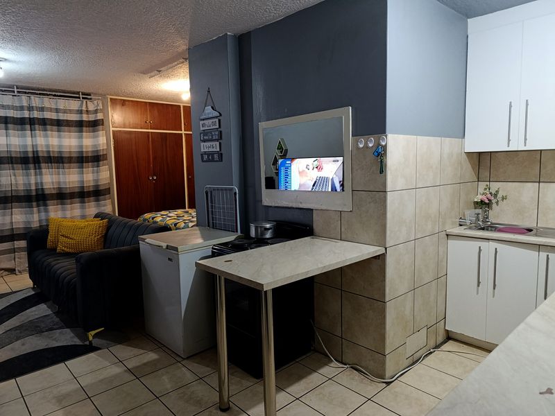 An open-plan living and kitchen area featuring tiled flooring, built-in cabinetry, and a functional kitchen workspace.